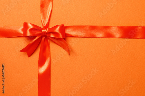 Orange ribbon and bow on an orange background. The concept of gifts.