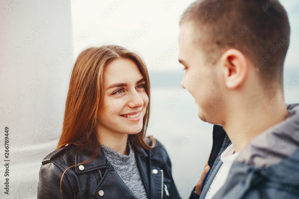 Cute couple standing near river. Boy and girl have fun in a autumn park Cute couple standing near river. Boy and girl have fun in a autumn park
