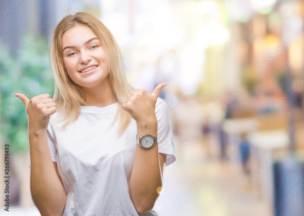 Young caucasian woman over isolated background success sign doing positive gesture with hand, thumbs up smiling and happy. Looking at the camera with cheerful expression, winner gesture.