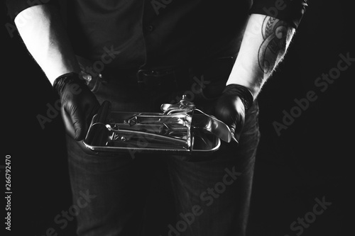 Man with metal speculum (medical). Latex gloves. BDSM concept.