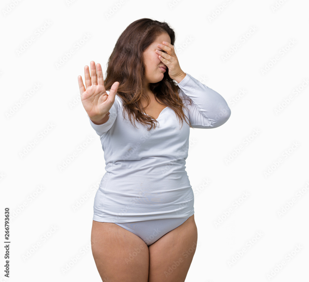 Foto de Beautiful plus size young overwight woman wearing white underwear  over isolated background covering eyes with hands and doing stop gesture  with sad and fear expression. Embarrassed do Stock