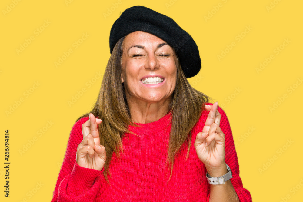 Middle age adult woman wearing fashion beret over isolated background smiling crossing fingers with hope and eyes closed. Luck and superstitious concept. Middle age adult woman wearing fashion beret over isolated background smiling crossing fingers with hope and eyes closed. Luck and superstitious concept.
