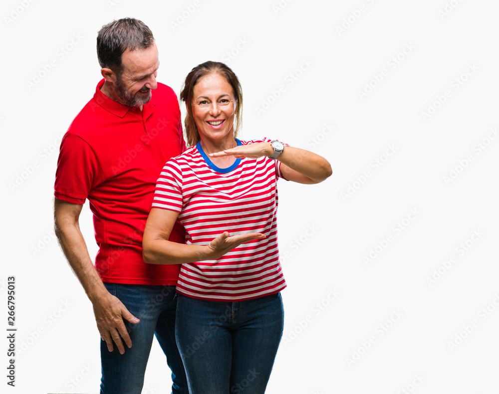 Middle age hispanic couple in love over isolated background gesturing with hands showing big and large size sign, measure symbol. Smiling looking at the camera. Measuring concept. Middle age hispanic couple in love over isolated background gesturing with hands showing big and large size sign, measure symbol. Smiling looking at the camera. Measuring concept.