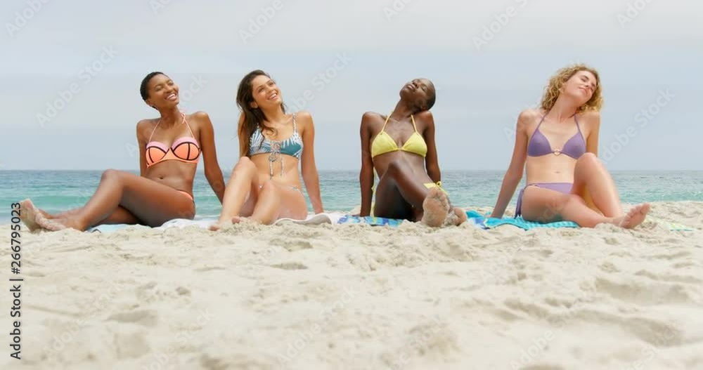 Front view of mixed-race female friends relaxing with eyes closed on the beach 4k Front view of mixed-race female friends relaxing with eyes closed on the beach 4k