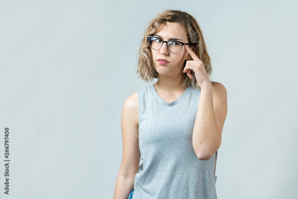 Fototapeta premium Emotional portrait of a fair-haired girl on a gray background, stormy emotions, business concept.