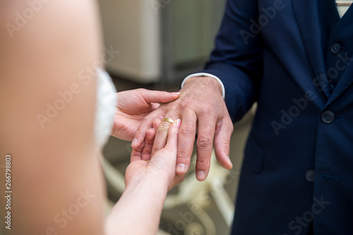 The bride wears a wedding ring on the groom.