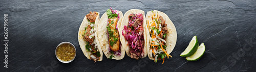 four mexican street tacos with fish barbacoa and carnitas shot in panoramic composition