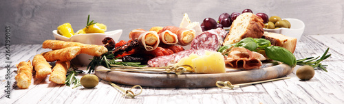 antipasto various appetizer. Cutting board with prosciutto, salami, cheese, bread and olives on white wooden background