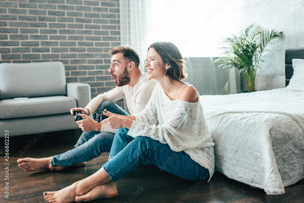 happy woman and emotional man playing video game at home