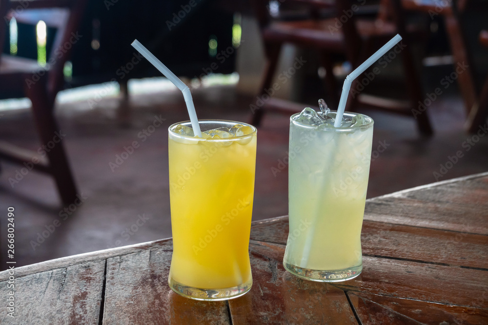 Two glasses of fresh orange and lemon juice on the table. Two glasses of fresh orange and lemon juice on the table.