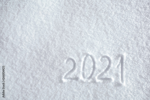Numbers, calendar date, inscription 2021 on natural snowy surface in wintertime. Text, Winter New Year holiday background, top view
