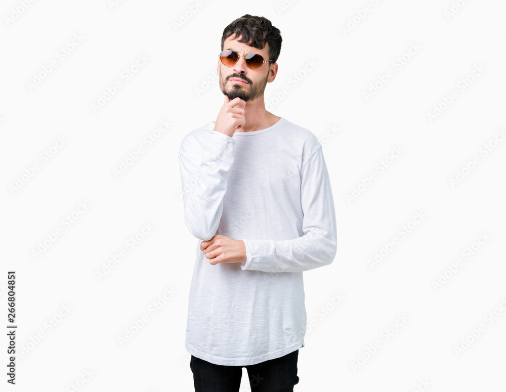 Young handsome man wearing sunglasses over isolated background with hand on chin thinking about question, pensive expression. Smiling with thoughtful face. Doubt concept. Young handsome man wearing sunglasses over isolated background with hand on chin thinking about question, pensive expression. Smiling with thoughtful face. Doubt concept.