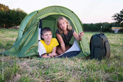 Smiling children lying in the tent in the park. Camping, tourism and teenagers activity or leisure concept. © Polina Ponomareva