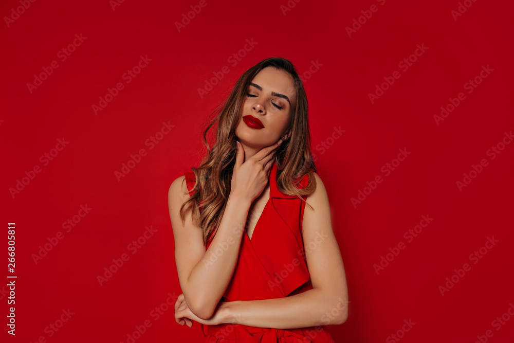 Elegant confident lady with gold hair enjoying photoshoot. Studio portrait of romantic young woman wearing red dress Elegant confident lady with gold hair enjoying photoshoot. Studio portrait of romantic young woman wearing red dress