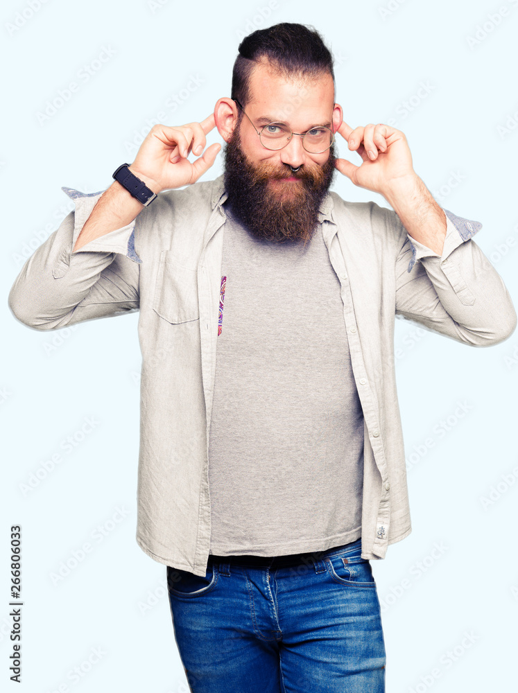 Fototapeta premium Young blond man wearing glasses Smiling pulling ears with fingers, funny gesture. Audition problem