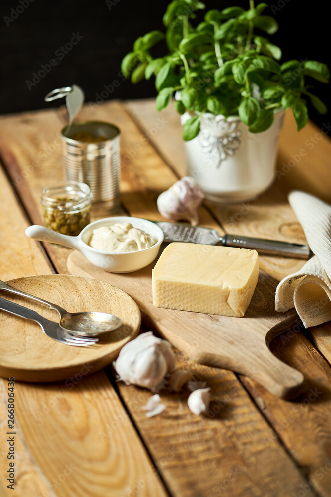 Cheese and grater fresh basil with can and sauce on wooden kitchen table Cheese and grater fresh basil with can and sauce on wooden kitchen table