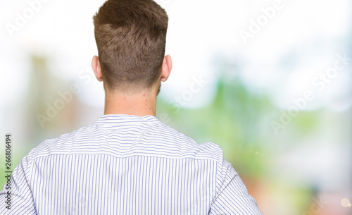 Young handsome man standing backwards looking away with arms on body