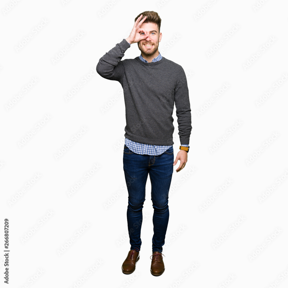Fototapeta premium Young handsome elegant man doing ok gesture with hand smiling, eye looking through fingers with happy face.