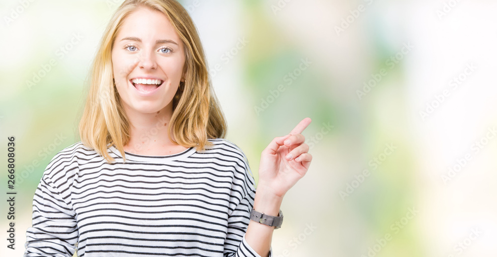 Beautiful young woman wearing stripes sweater over isolated background with a big smile on face, pointing with hand and finger to the side looking at the camera. Beautiful young woman wearing stripes sweater over isolated background with a big smile on face, pointing with hand and finger to the side looking at the camera.
