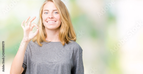 Beautiful young woman wearing oversize casual t-shirt over isolated background smiling positive doing ok sign with hand and fingers. Successful expression.