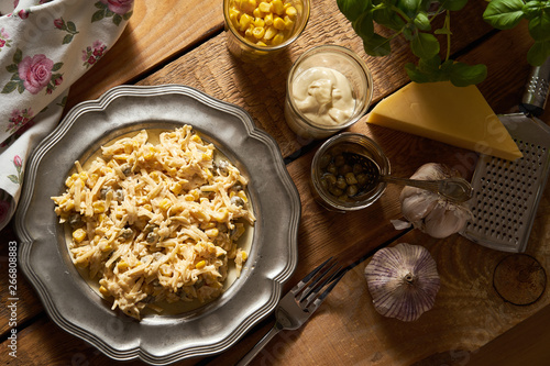 Salad of grated cheese with capers and corn with basil on wooden table