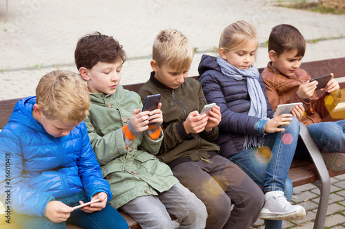 Five kidsare chatting on their smartphone