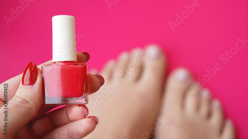 Young perfect groomed womans feet on pink background. Care about nails and clean  soft  smooth body skin. Pedicure and manicure beauty salon