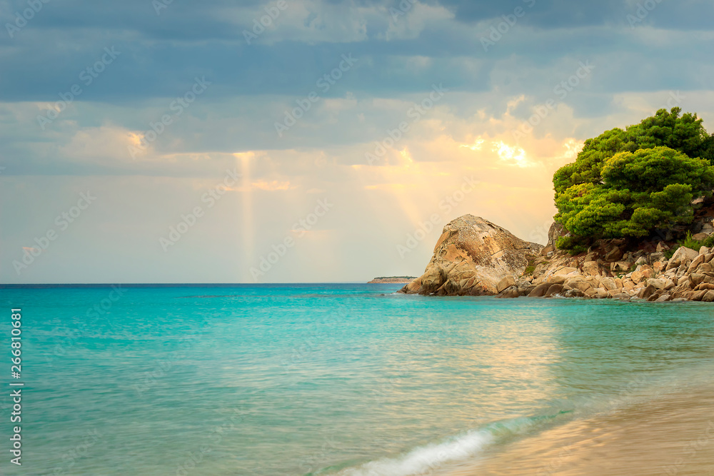 Sun rays passing through the clouds and falling on turquoise sea water of Koviou beach and beautiful rocks Sun rays passing through the clouds and falling on turquoise sea water of Koviou beach and beautiful rocks
