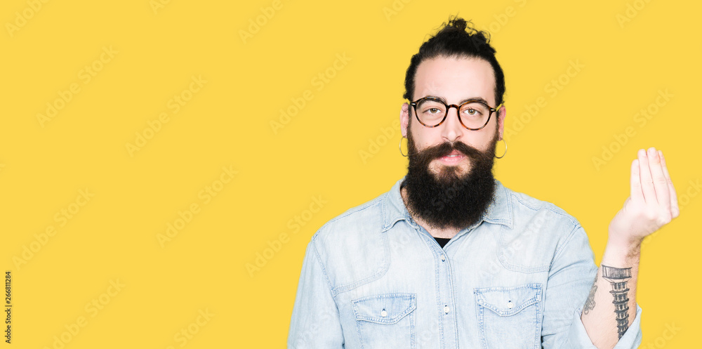 Fototapeta premium Young hipster man with long hair and beard wearing glasses Doing Italian gesture with hand and fingers confident expression