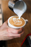 barista man preparing coffee (cappuccino with a swan latte art), pouring milk