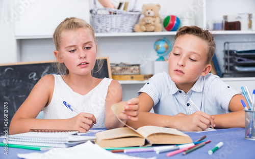 Boy with girl are writing in notebook their homework