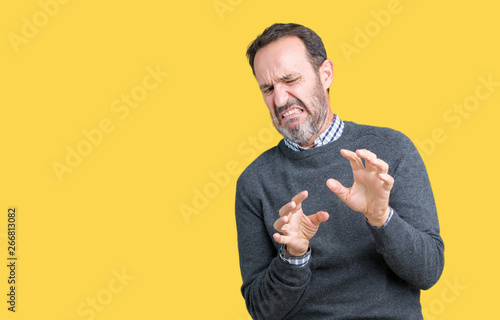 Handsome middle age senior man wearing a sweater over isolated background disgusted expression, displeased and fearful doing disgust face because aversion reaction. With hands raised