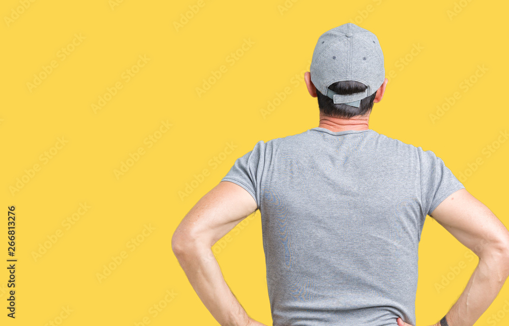 Handsome middle age hoary senior man wearing sport cap over isolated background standing backwards looking away with arms on body
