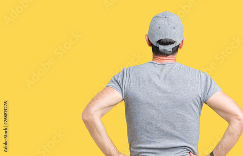 Handsome middle age hoary senior man wearing sport cap over isolated background standing backwards looking away with arms on body © Krakenimages.com