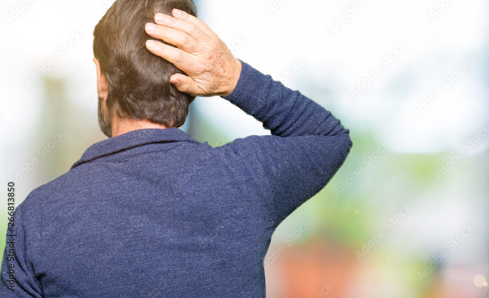 Middle age handsome man wearing a sweater Backwards thinking about doubt with hand on head