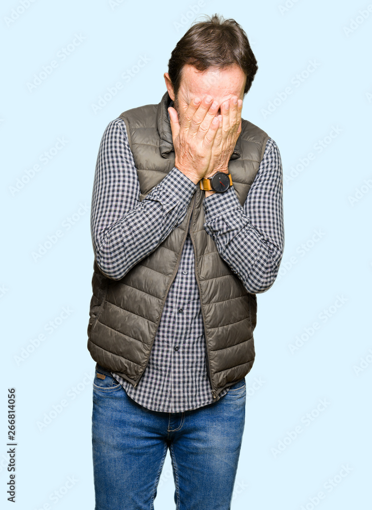 Middle age handsome man wearing winter vest with sad expression covering face with hands while crying. Depression concept. Middle age handsome man wearing winter vest with sad expression covering face with hands while crying. Depression concept.