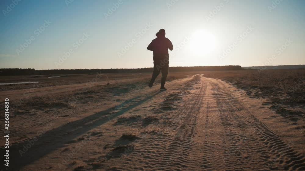 Running man silhouette in sunset time. Outdoor cross-country running. Athletic young man is running in the nature during golden sunset. Healthy lifestyle. Running man silhouette in sunset time. Outdoor cross-country running. Athletic young man is running in the nature during golden sunset. Healthy lifestyle.