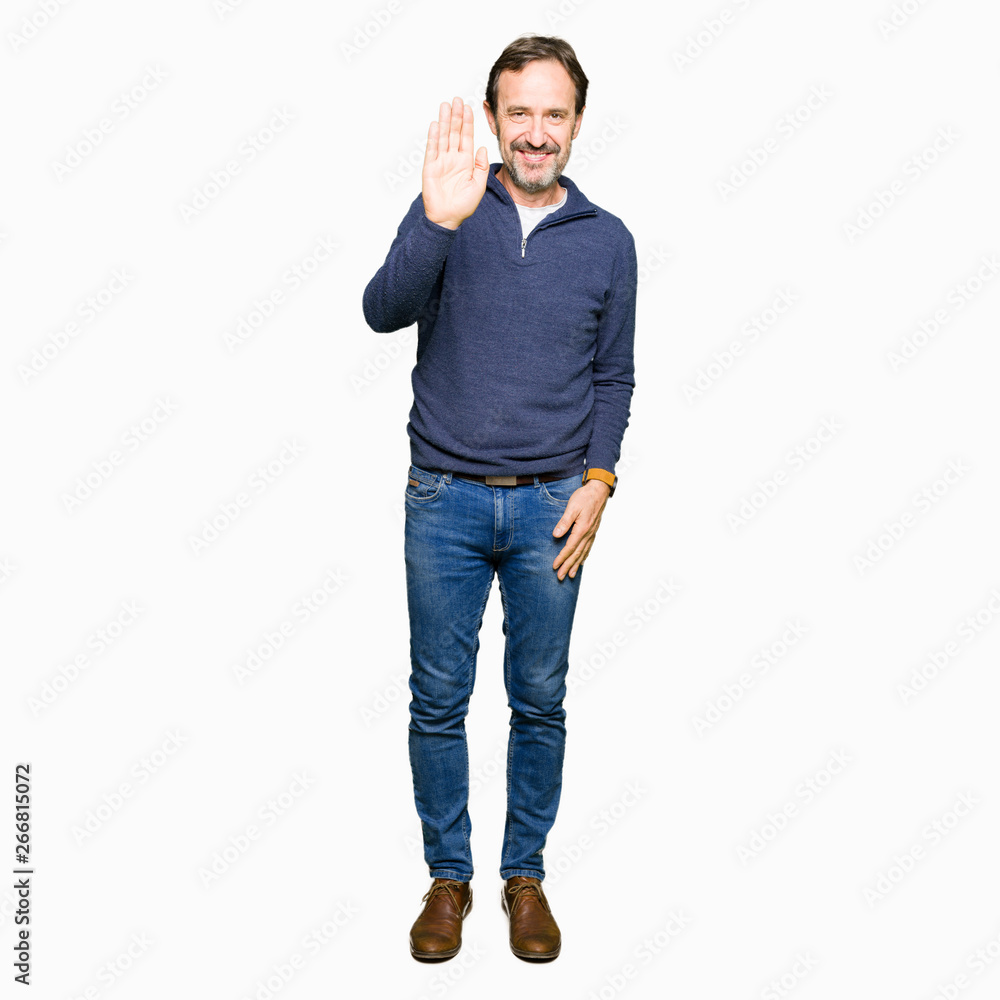 Middle age handsome man wearing a sweater Waiving saying hello happy and smiling, friendly welcome gesture Middle age handsome man wearing a sweater Waiving saying hello happy and smiling, friendly welcome gesture