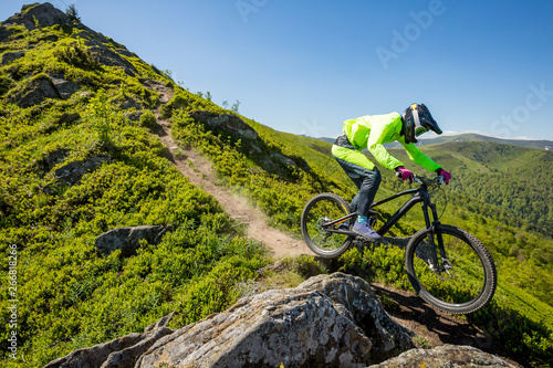 Professional athlete is riding enduro bicycle on a beautiful rocky trail.