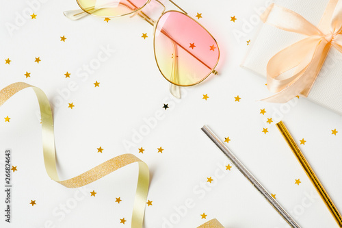 Summer party accessories over white background. Festive stuff, confetti stars, ribbon, sunglasses, gift box. Invitation, birthday, beach party, hen party concept