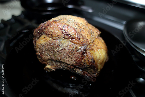 Baked prime rib roast resting on the stove top in a cast iron skillet. 