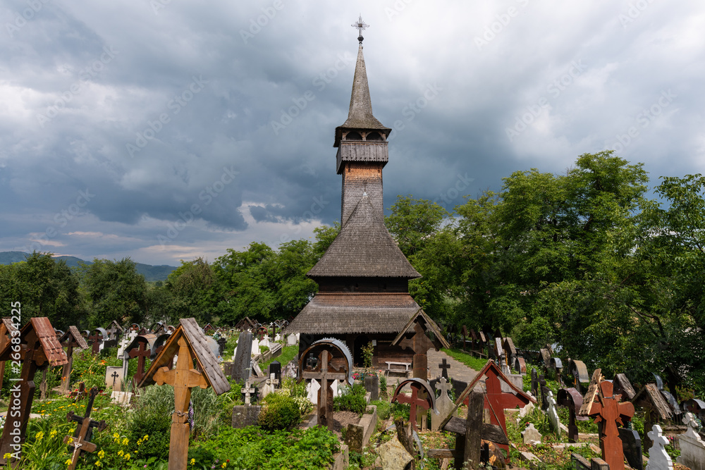 Ieud, Maramures, Romania - July 9, 2018: Ieud Hill Church and its graveyard, the oldest wood church in Maramures, Romania under a dramatic sky.