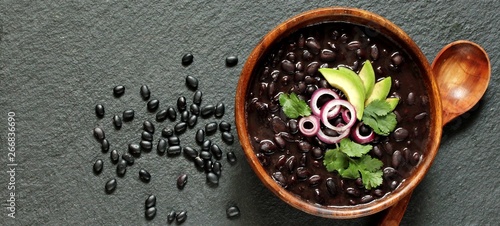 thick black bean soup or stew. Latin American or Mexican cuisine. stewed black beans served with avocado and red onion and cilantro. place for text. top view. photo