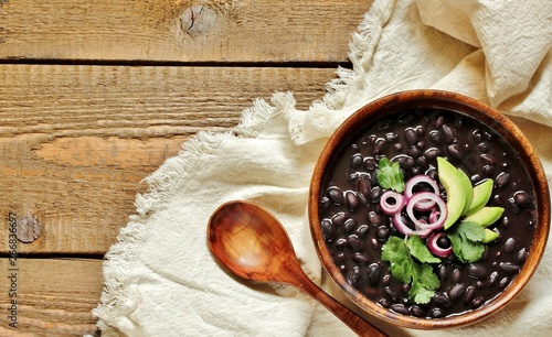 thick black bean soup or stew. Latin American or Mexican cuisine. stewed black beans served with avocado and red onion and cilantro. place for text. top view.