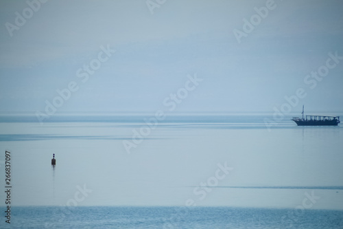 Fishing boat out on the Sea of Galille on a hazy morning, barely visible © shellybychowskishots