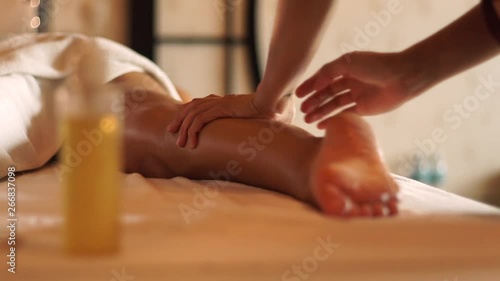 Young woman getting legs massage with oil in resort spa salon. Young woman receiving body massage in luxury spa center. Body relaxation and skin care.