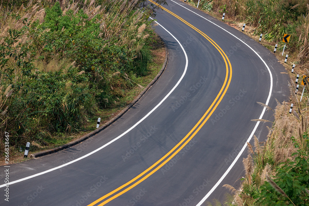 Asphalt road winding on the mountains with yellow and white traffic lines.