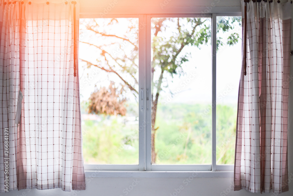 Sunlight through in room open curtains with balcony and nature tree on outside window - bedroom window in the morning Sunlight through in room open curtains with balcony and nature tree on outside window - bedroom window in the morning