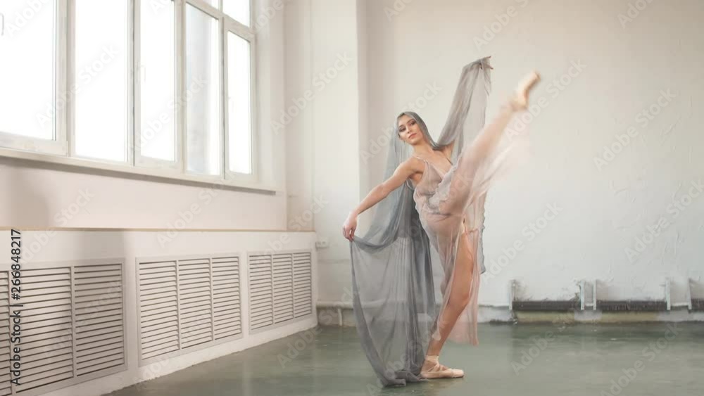 Beautiful dark-haired Arabian female dancer dancing in grey transparent costume with cape on head in white studio Beautiful dark-haired Arabian female dancer dancing in grey transparent costume with cape on head in white studio