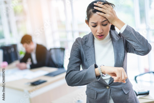 Young attractive Asian business woman looking at the watch time worried and afraid of getting late to meeting with boss or customer. photo
